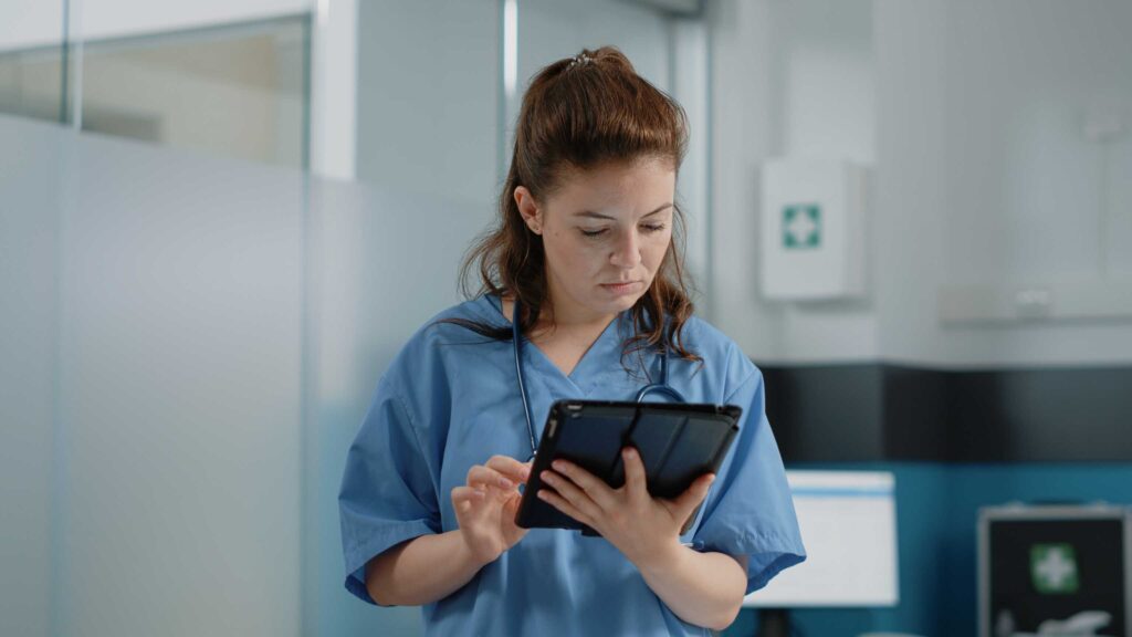 A nurse holding tablet in a hand and doing something.